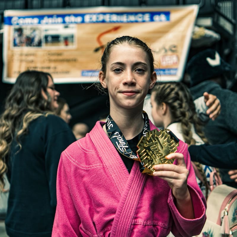 Young athlete in pink gi with JJWL Finals gold medal