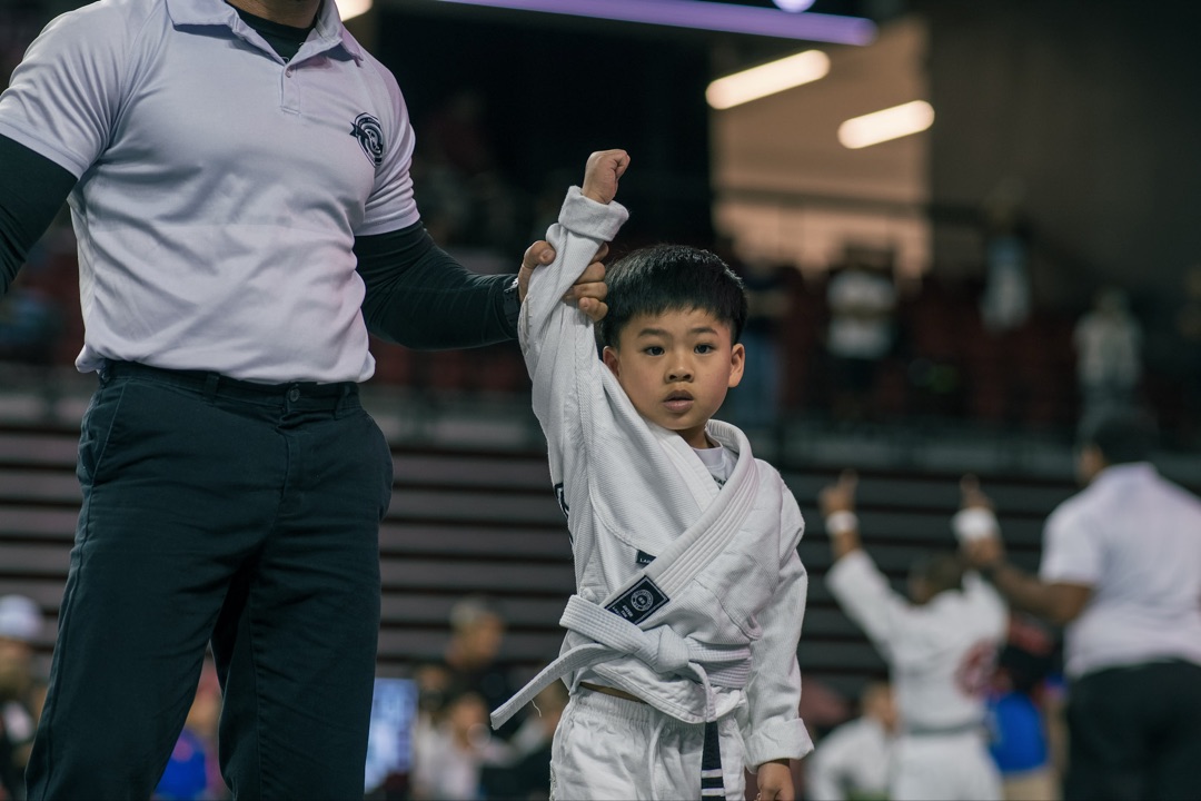 Young boy in white gi with hand raised