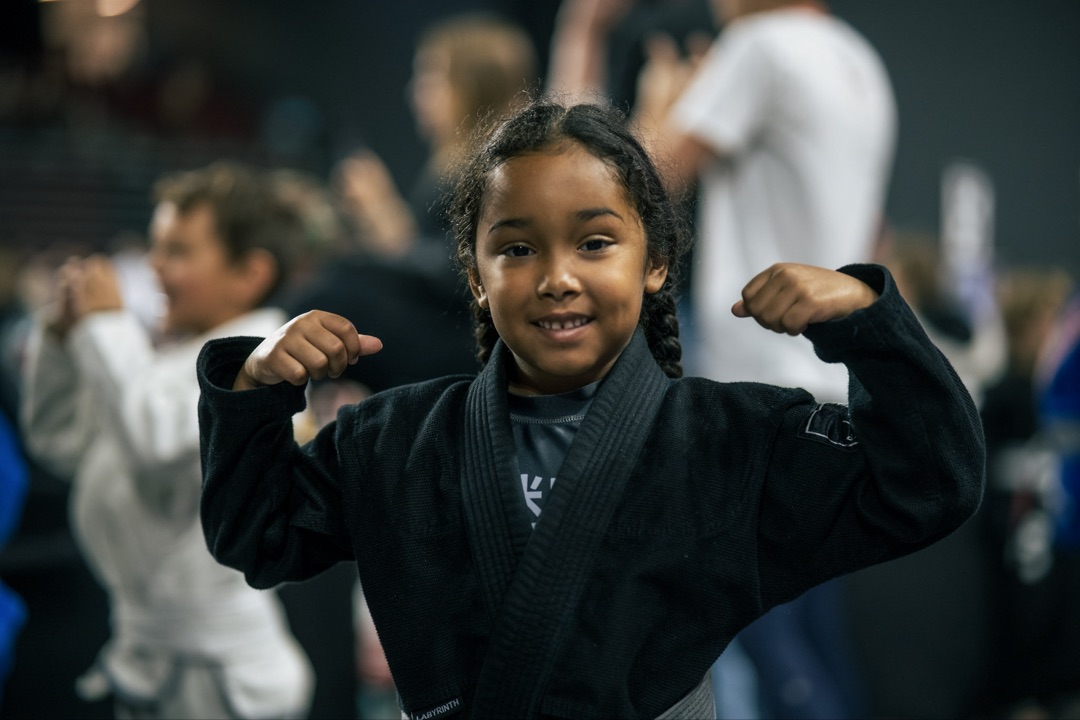 Young Labyrinth BJJ athlete flexing in her gi at a competition